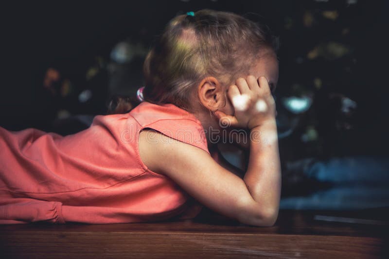 Bored lonely child girl lying on windowsill in home isolation opposite window royalty free stock images
