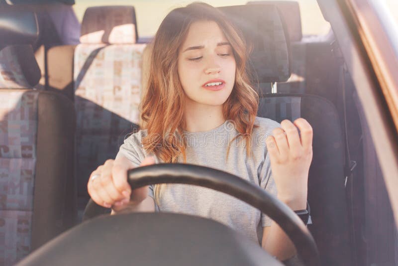 Bored mooie jonge dame bekijkt haar manicure terwijl de tribunes in opstopping bij auto, die succesvolle bestuurder expericed zij royalty-vrije stock foto Bored mooie jonge dame bekijkt haar manicure terwijl de tribunes in opstopping bij auto, die succesvolle bestuurder expericed zij royalty-vrije stock foto