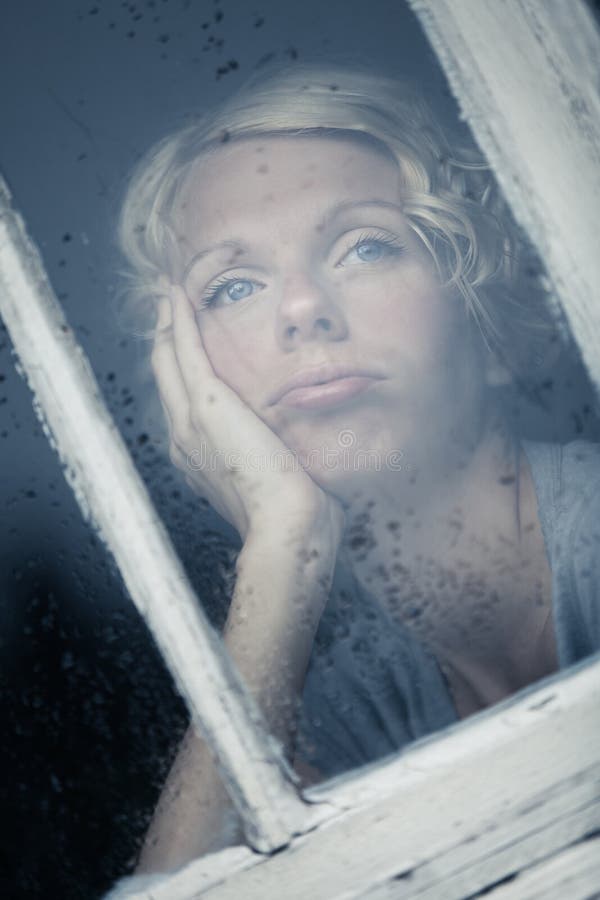 Bored Woman Looking at the Rainy Weather By the Window stock photo