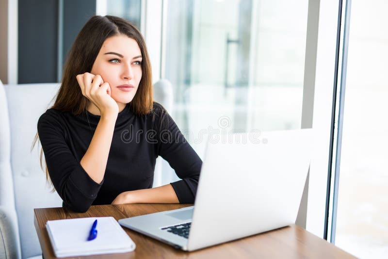 Bored young woman in the office working with a laptop stock photography