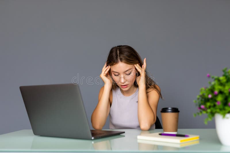 Bored young woman in the office working with a laptop and staring at screen stock photo