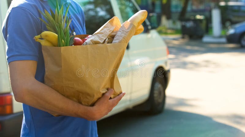 Delivery worker holding grocery bag with fresh tasty goods, supermarket service, stock photo. Delivery worker holding grocery bag with fresh tasty goods, supermarket service, stock photo