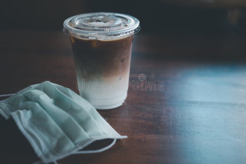 Borttagen plats för den kirurgiska masken på bordet med iskaffe latte fotografering för bildbyråer