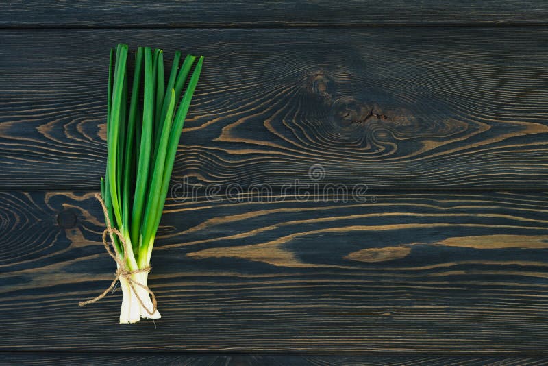 Bos van verse groene uiensjalotten in bundel op broodplanklijst Donkere of neutrale houten achtergrond royalty-vrije stock foto's Bos van verse groene uiensjalotten in bundel op broodplanklijst Donkere of neutrale houten achtergrond royalty-vrije stock foto's