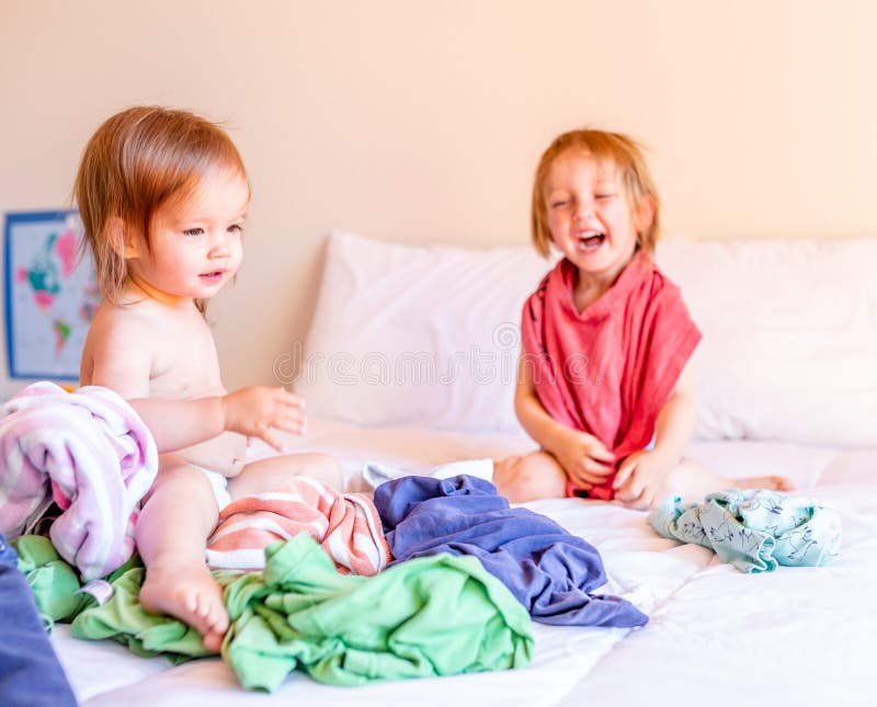 Boshafter Bruder und Schwester Play in einem Stapel der W?scherei auf dem Bett Aufbau mit Schrauben und Muttern lizenzfreies stockbild Boshafter Bruder und Schwester Play in einem Stapel der W?scherei auf dem Bett Aufbau mit Schrauben und Muttern lizenzfreies stockbild