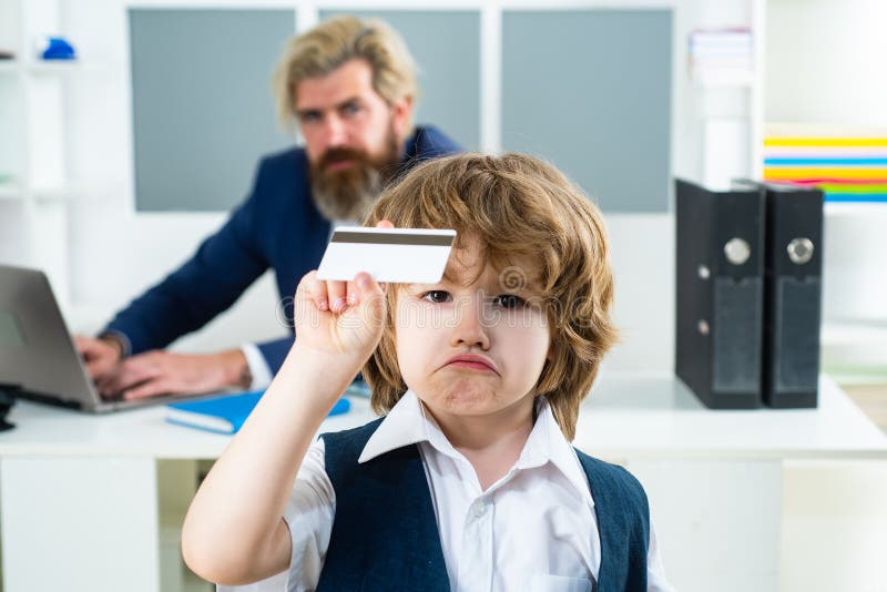Boss businessman holding credit card. Young business boy. Funny child in office holding Business card. Serious boy stock image Boss businessman holding credit card. Young business boy. Funny child in office holding Business card. Serious boy stock image