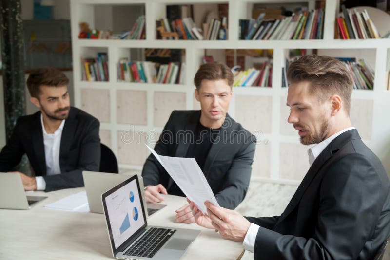 Boss looking at financial stats report presented by employee.