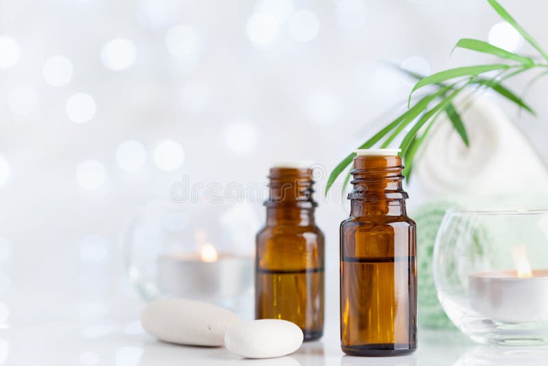 Botella con aceite esencial, la toalla y las velas en la tabla blanca Balneario, aromatherapy, salud, fondo de la belleza