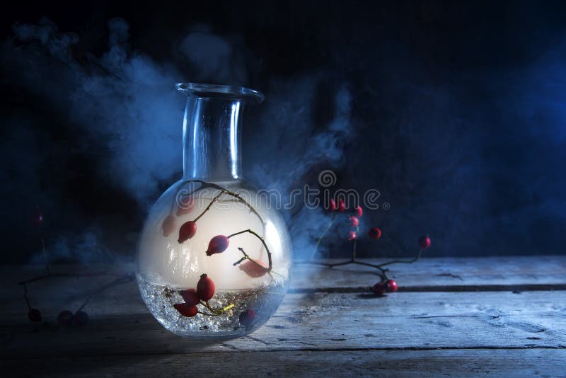 Botella con humo que brilla intensamente y escaramujos dentro en un woode rústico imagen de archivo libre de regalías Botella con humo que brilla intensamente y escaramujos dentro en un woode rústico imagen de archivo libre de regalías