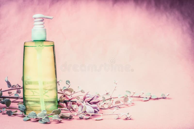 Natural cosmetic product bottle with green lotion or tonic liquid with fresh herbs and flowers at pink background. Healthy skin or body care, beauty , spa or wellness concept, front view, copy space. Natural cosmetic product bottle with green lotion or tonic liquid with fresh herbs and flowers at pink background. Healthy skin or body care, beauty , spa or wellness concept, front view, copy space