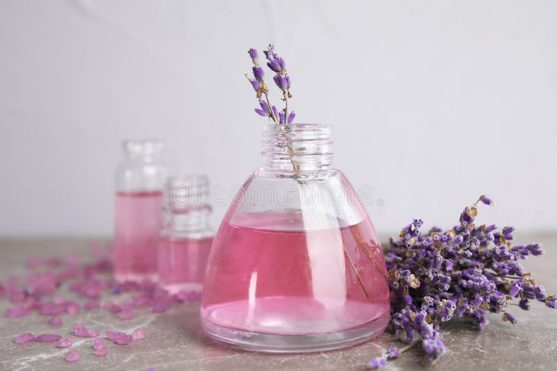 Botellas con aceite de lavanda aromático en la tabla gris imagenes de archivo Botellas con aceite de lavanda aromático en la tabla gris imagenes de archivo