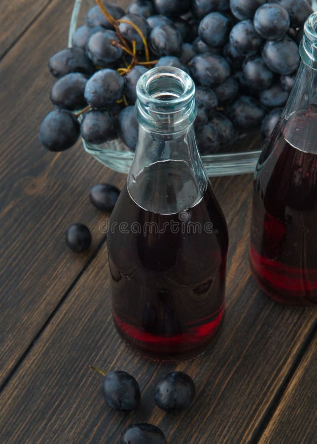 Botellas de cristal de vino rojo joven fresco con un manojo de grap negro imagenes de archivo