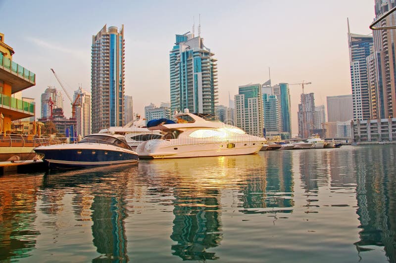 Several boats and yachts berthed in the Dubai Marina with luxury apartments in the background. Several boats and yachts berthed in the Dubai Marina with luxury apartments in the background