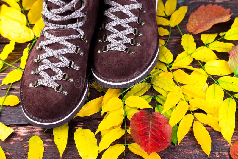 Bottes de suède d'homme de Brown sur le fond en bois avec des feuilles Chaussures d'automne ou d'hiver images libres de droits Bottes de suède d'homme de Brown sur le fond en bois avec des feuilles Chaussures d'automne ou d'hiver images libres de droits