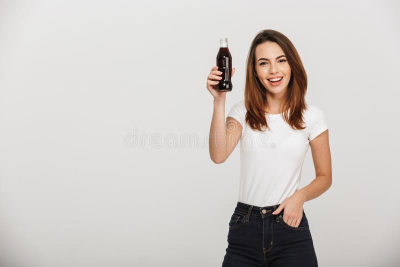 Bottiglia allegra della tenuta della giovane donna con soda immagine stock Bottiglia allegra della tenuta della giovane donna con soda immagine stock