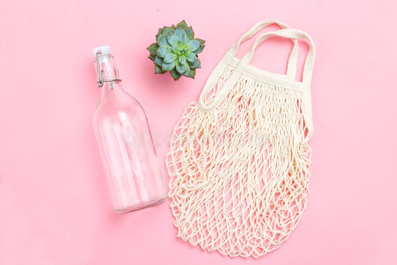 Reusable bottle and reusable mesh bag on pink background. Sustainable lifestyle. Succulents. Reusable bottle and reusable mesh bag on pink background. Sustainable lifestyle. Succulents