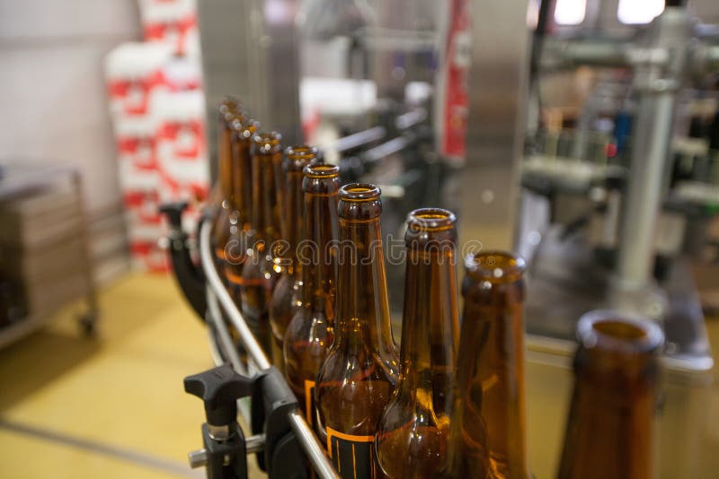 Bottiglie di birra vuote, su un nastro trasportatore, fabbrica di birra obbligatoria fotografia stock Bottiglie di birra vuote, su un nastro trasportatore, fabbrica di birra obbligatoria fotografia stock