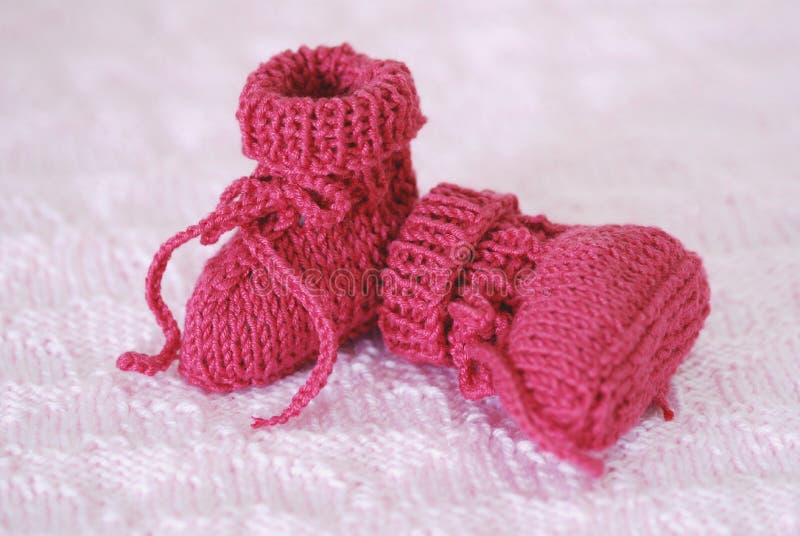 A pair of knitted, bright pink baby booties. A pair of knitted, bright pink baby booties