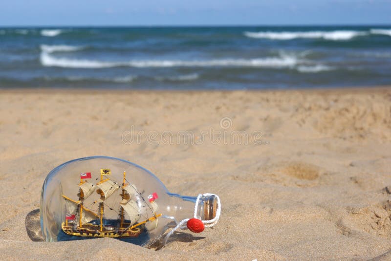 Bottle with a boat on the beach by the sea, a real treasure royalty free stock photo
