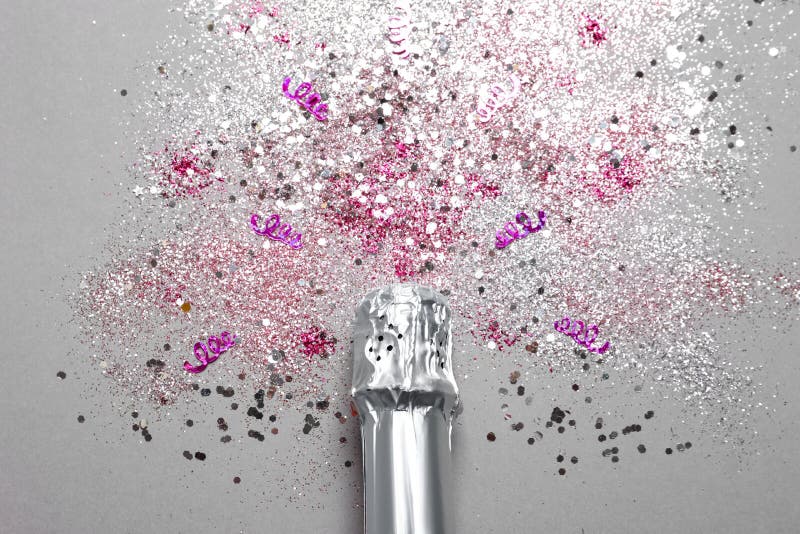 Bottle of champagne for celebration with glitter and confetti on grey background