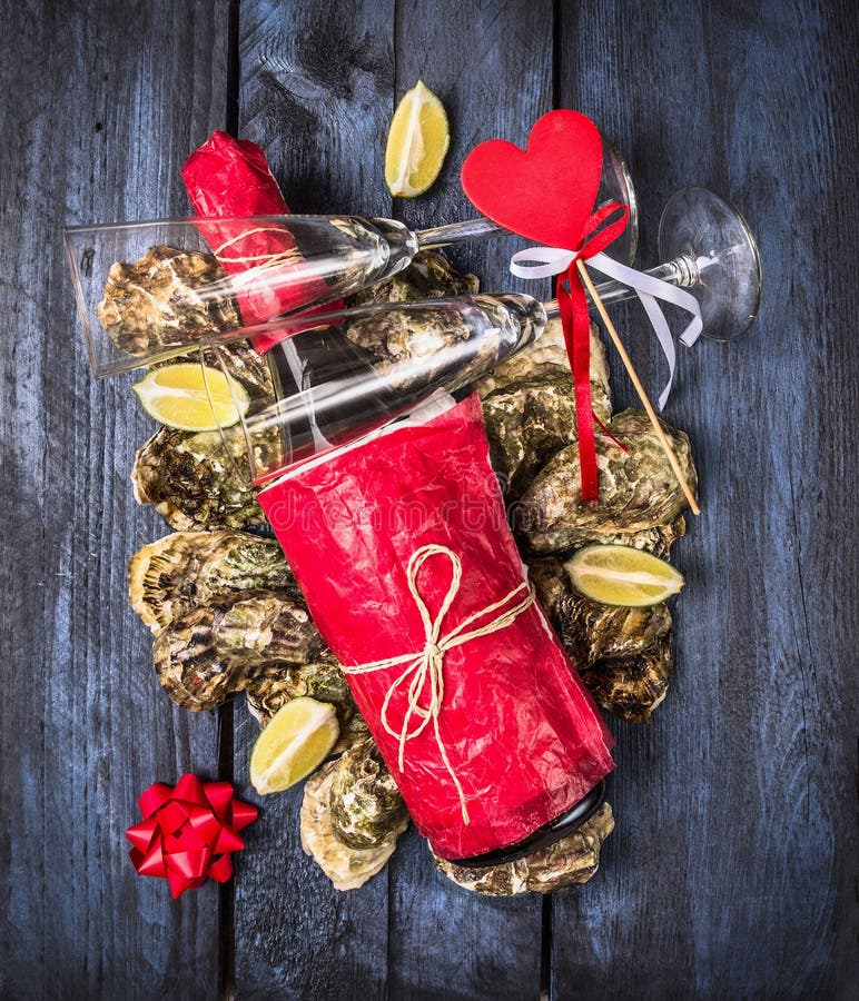 Bottle of champagne, glass , red heard and Oysters with lemon on blue wooden background