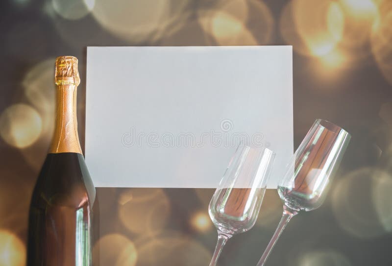 Bottle of champagne and two empty glasses with empty card for your notes.