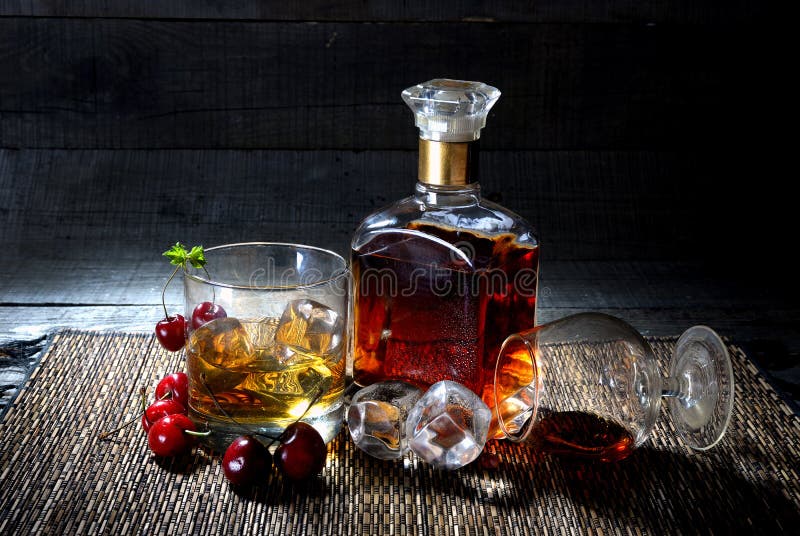 A bottle of cognac,whiskey with two glasses and fruits on wooden background