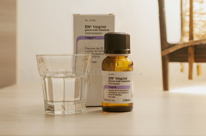 Bottle of EN benzodiazepines, delorazepam on a bedside table with a glass of water. This drug is used to treat anxious states