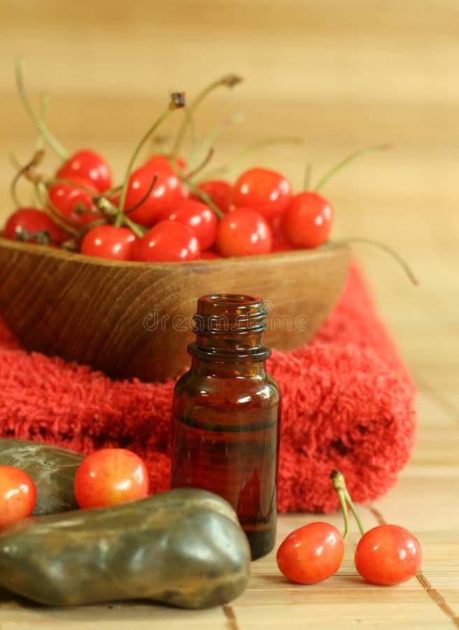 Bottle of essence oil, fresh cherry and red towel