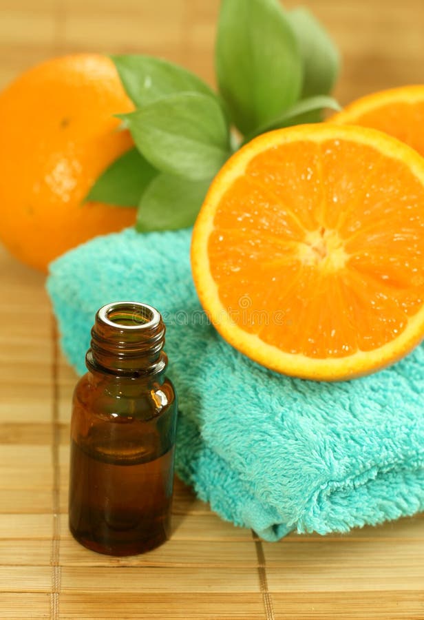 Bottle of essence oil, towel and fresh oranges
