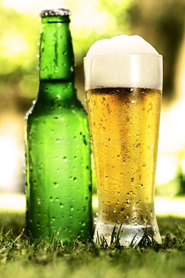 Bottle and glass of beer outside on the grass