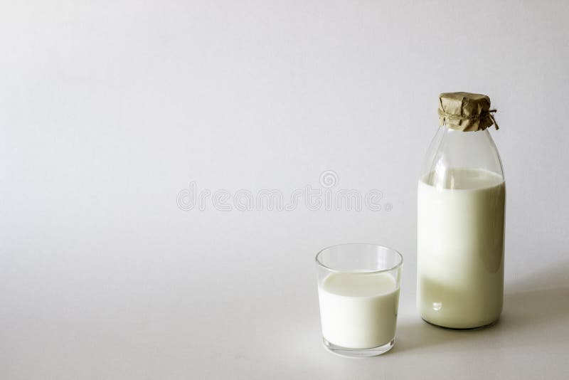 A bottle and glass of milk on a grey background. Minimalism stock photo A bottle and glass of milk on a grey background. Minimalism stock photo