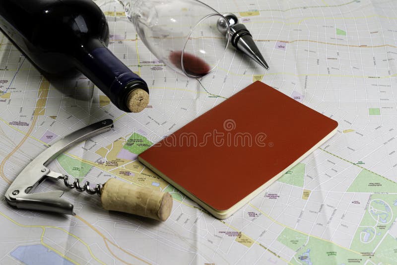 Bottle and glass of wine and corks on map for route planning. Red notebook for notes royalty free stock photography Bottle and glass of wine and corks on map for route planning. Red notebook for notes royalty free stock photography