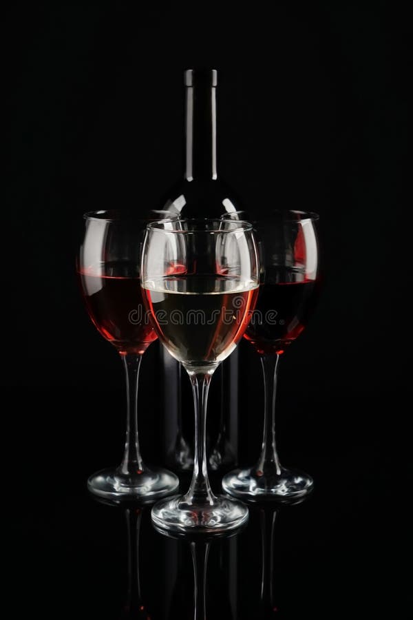 Bottle and glasses of red wine on dark background