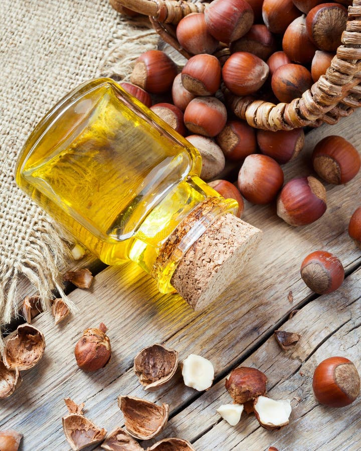 Bottle of nut oil and basket with hazelnuts on old kitchen table