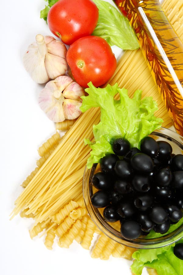 A bottle of olive oil with pasta and black olives