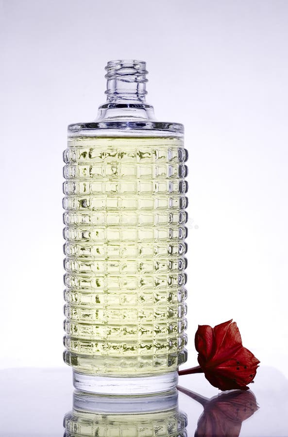 Bottle of perfume with flower and reflection.