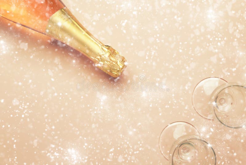 Bottle with pink sparkling wine or rose champagne and glasses under the snow, pink background with place for text, holiday or date