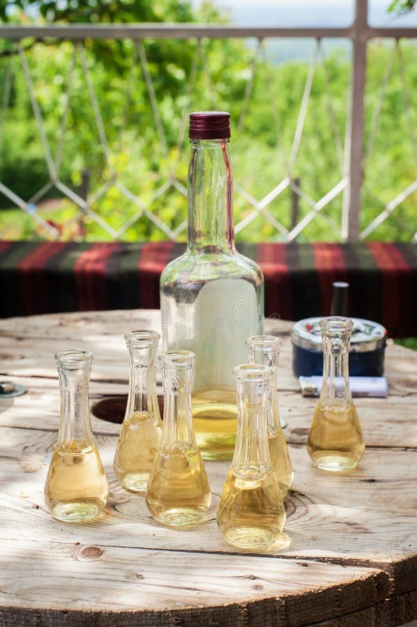 Bottle of plum brandy with small glasses on wooden table