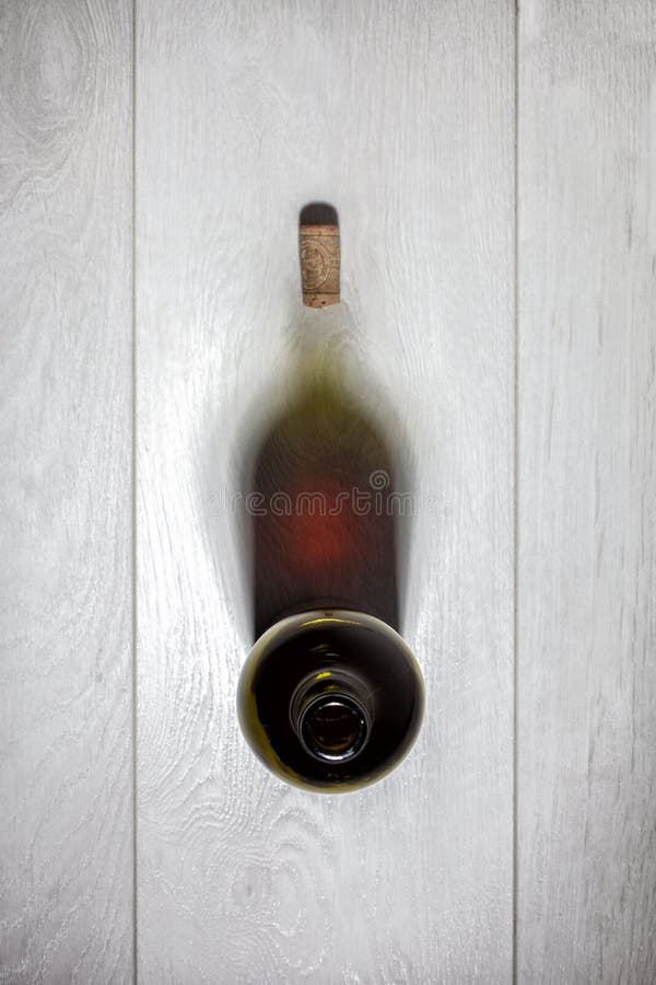 Bottle of red wine with cork on white wooden table