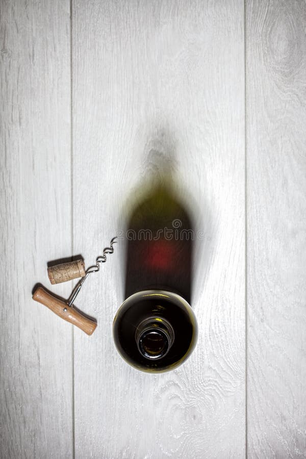 Bottle of red wine with cork on white wooden table