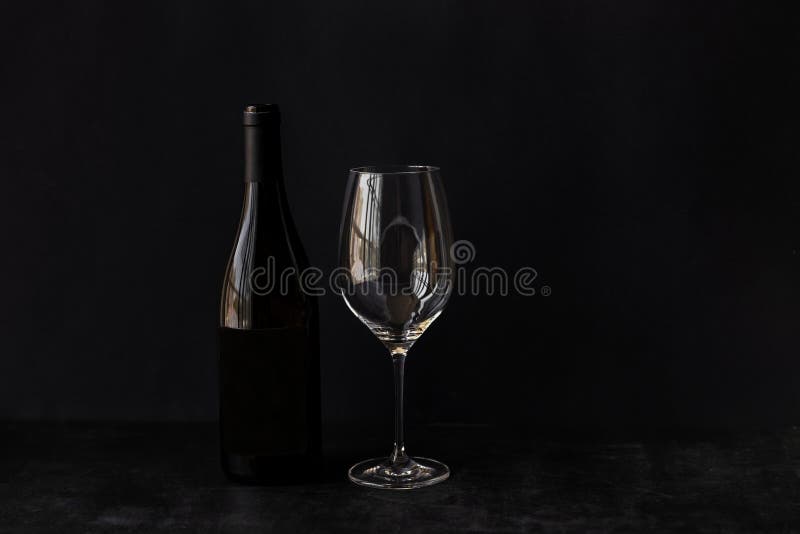 A bottle of red wine and a glass on a black background. stock image