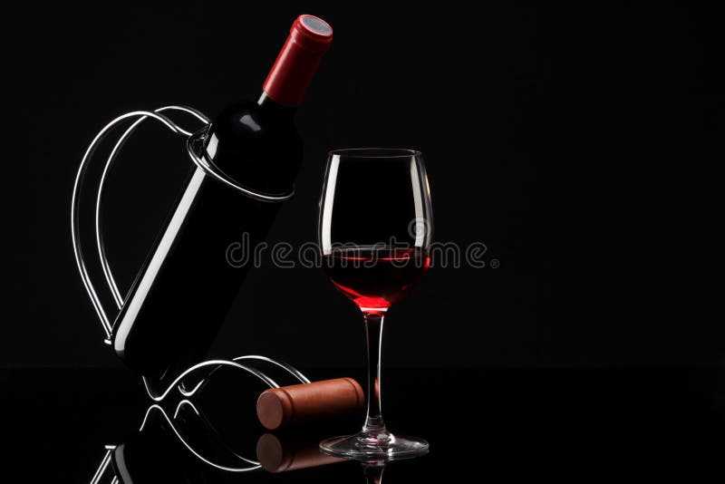 Bottle with red wine on a stand and glass