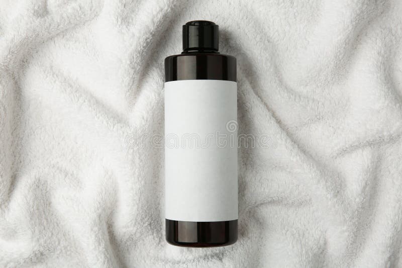 Bottle of shampoo on soft terry towel, top view stock photos