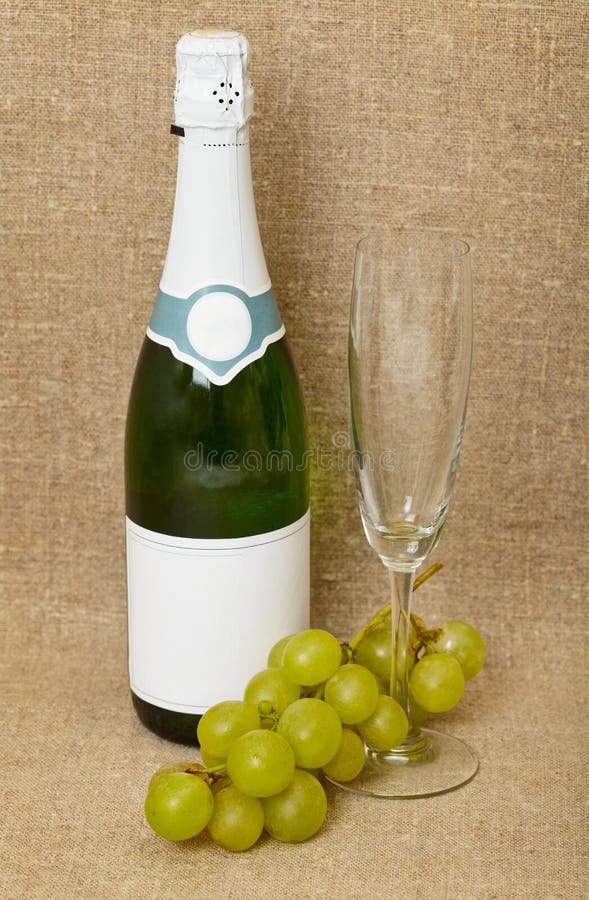 Bottle of sparkling wine, glass and grapes