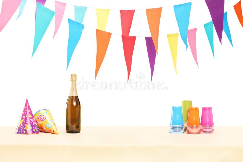 Bottle of sparkling wine, plastic glasses and party hats isolated on white background