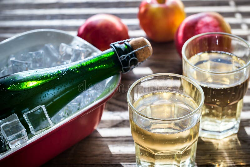 Bottle and two glasses of cider on the wooden background