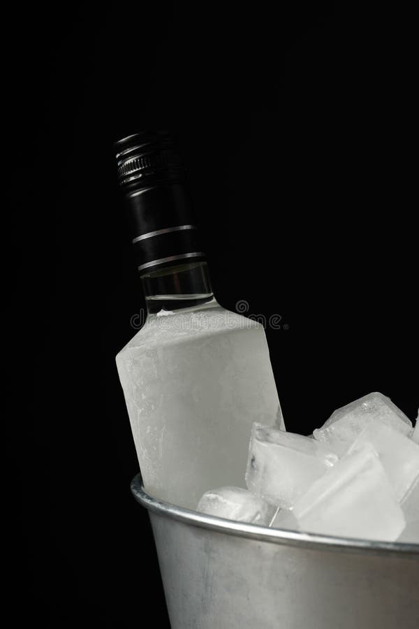 Bottle of Vodka in Metal Bucket with Ice on Black Background Stock