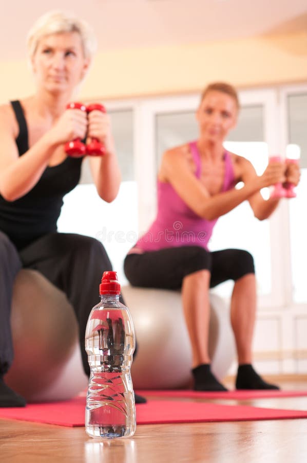 Bottle of water in front of group doing fitness