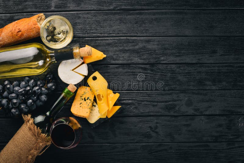 A bottle of wine, grapes and cheese on a wooden background. Cheese brie, blue cheese, gorgonzola, fuete, salami. royalty free stock image A bottle of wine, grapes and cheese on a wooden background. Cheese brie, blue cheese, gorgonzola, fuete, salami. royalty free stock image